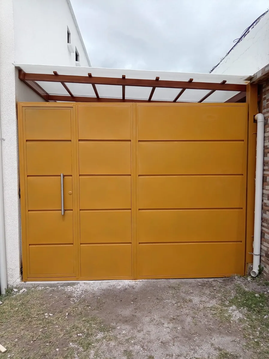 Portón metálico batiente color dorado con puerta peatonal en Quito