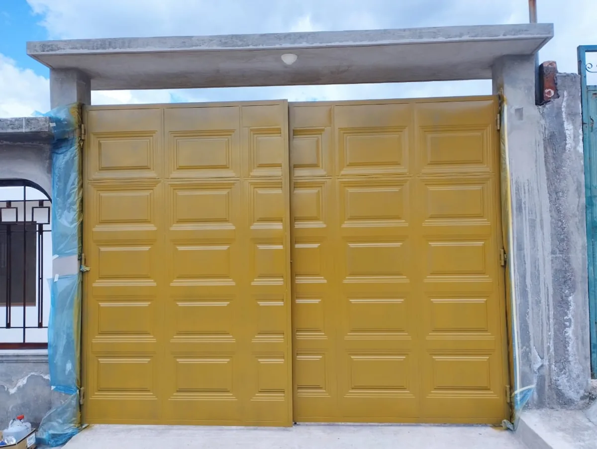 Portón metálico de tableros color dorado en Quito
