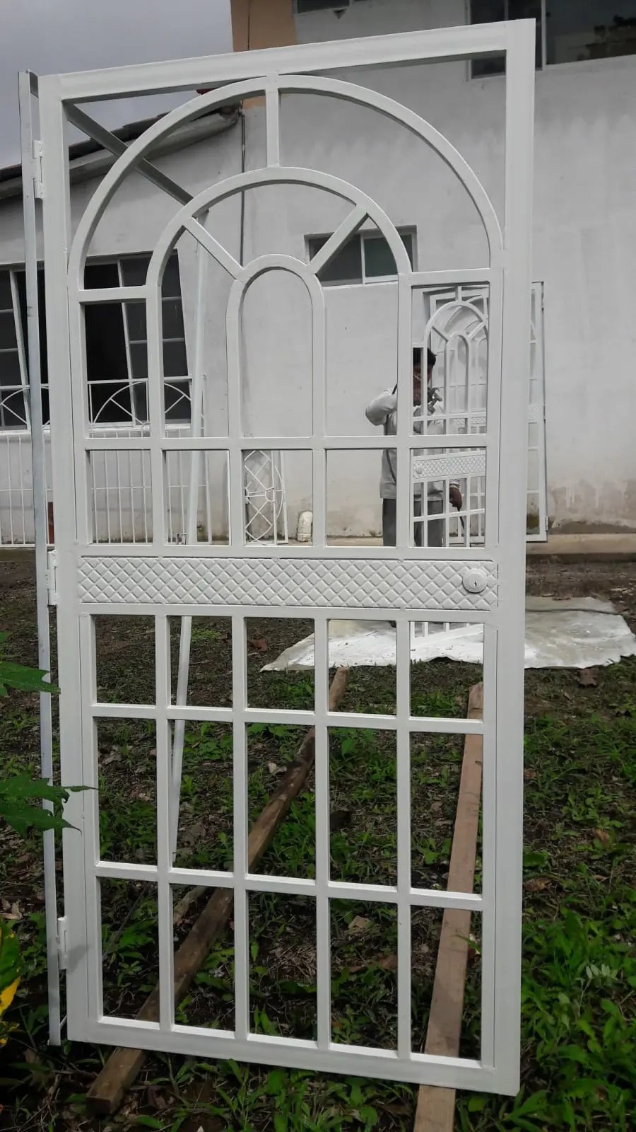 Cubre-puerta blanco de reja cuadriculada con arco superior