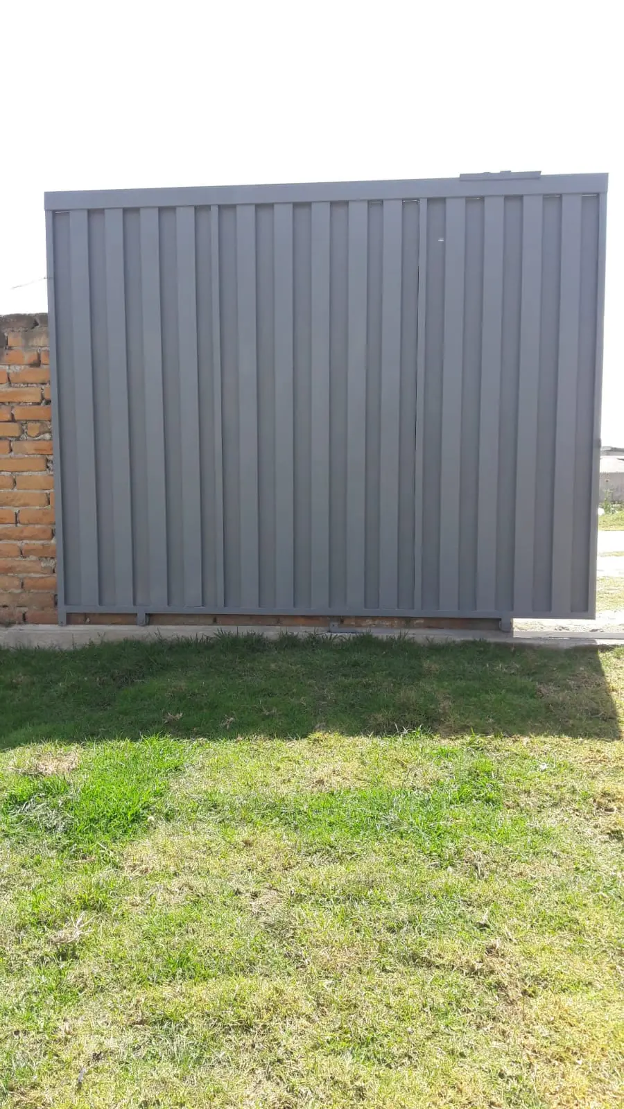 Portón de garaje gris de chapa lisa instalado en exterior