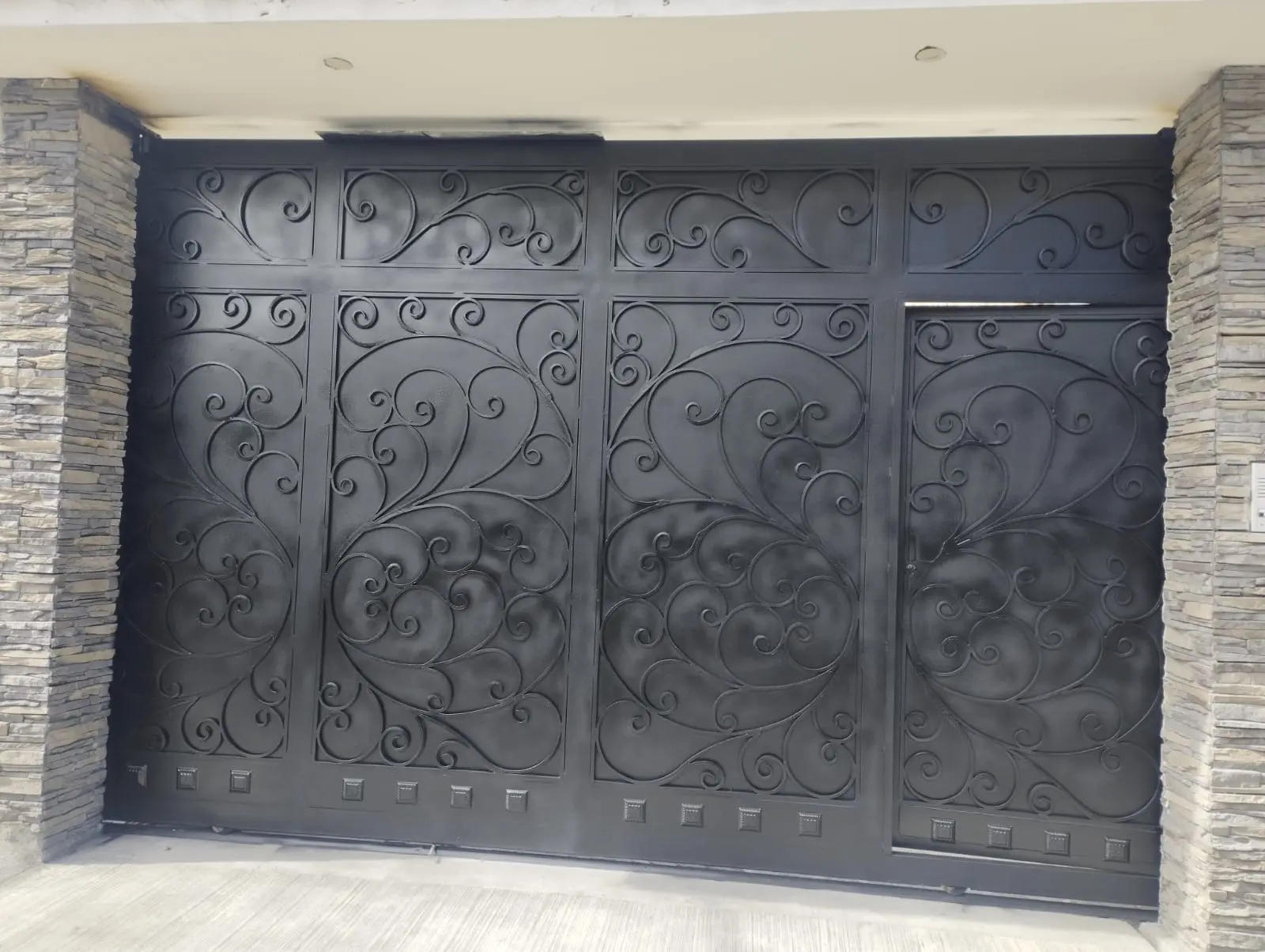 Portón de garaje en hierro forjado con ornamentación floral, fabricado a medida en Quito