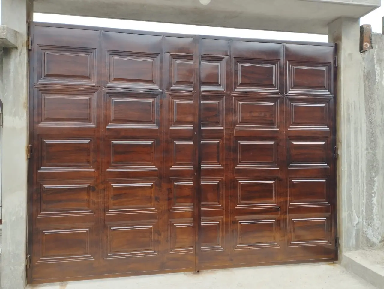 Portón de garaje metálico con acabado imitación madera y tableros