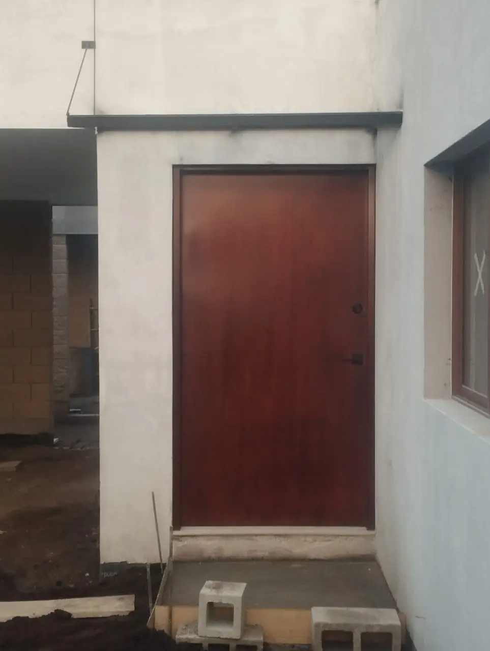 Puerta metálica tamborada color vino instalada en obra