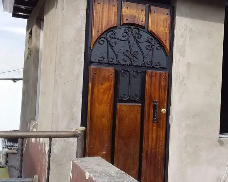 Puerta mixta de madera y hierro forjado con arco superior
