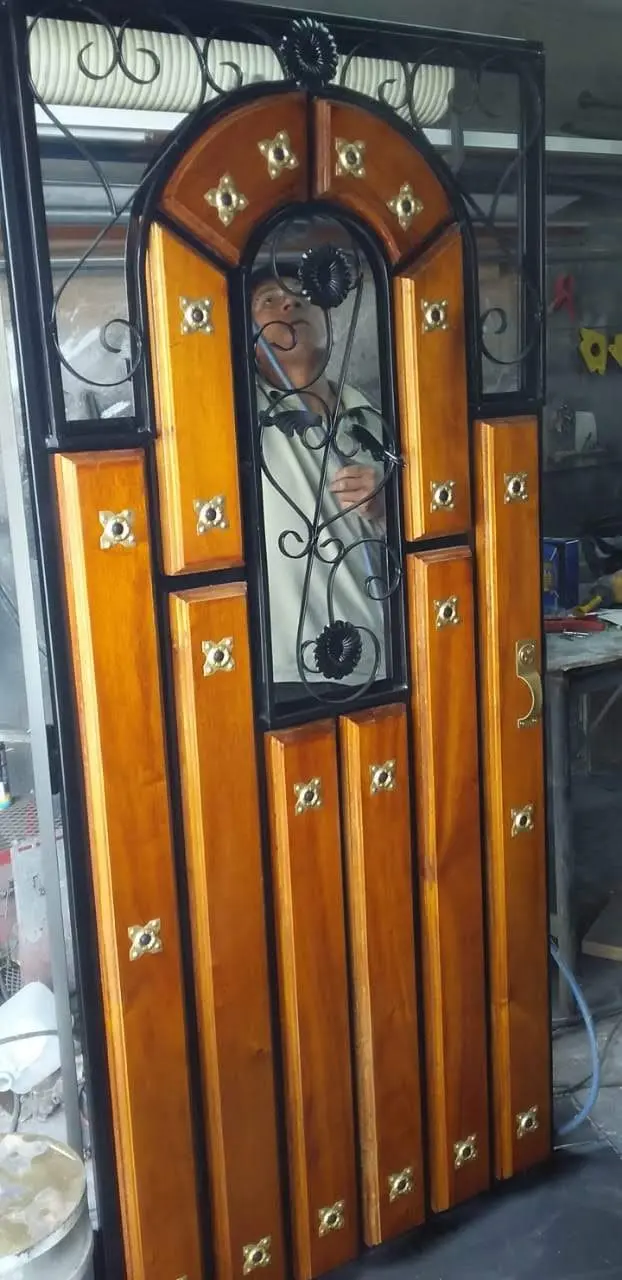 Puerta mixta de madera y hierro con arco decorado y vitral