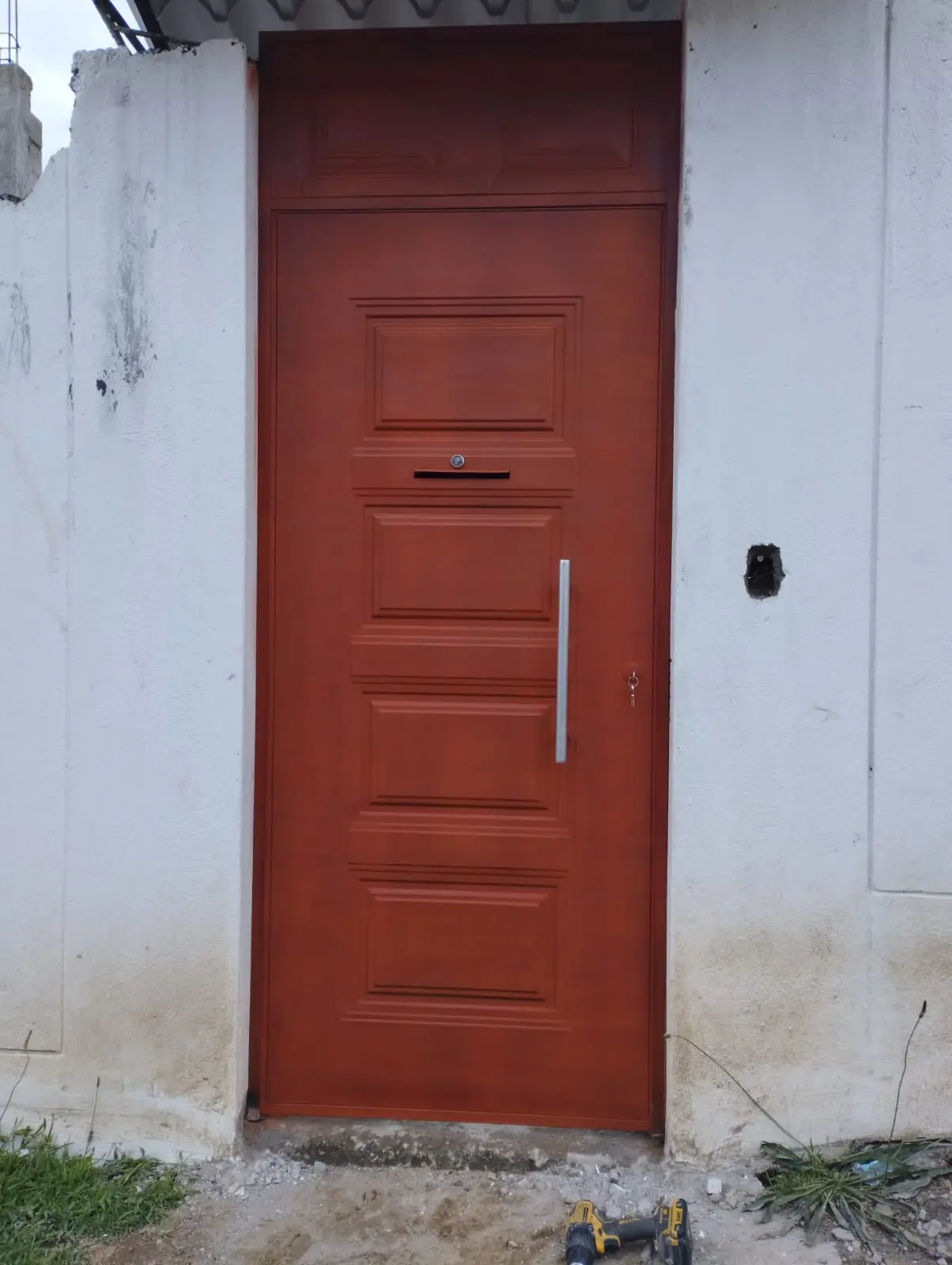 Puerta peatonal de hierro color rojo con tablero y manillón vertical