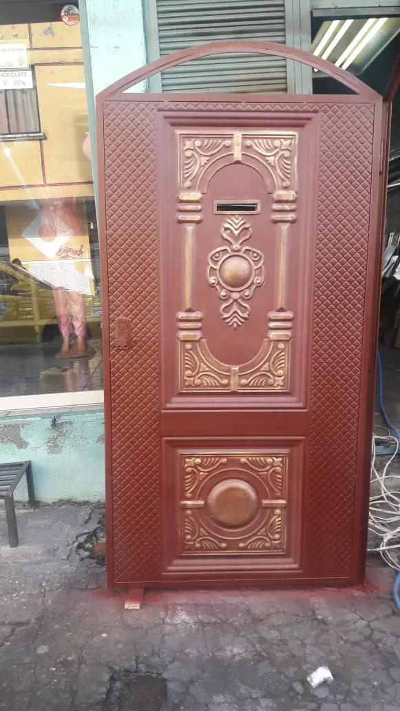 Puerta de tool color terracota con tableros repujados y arco superior