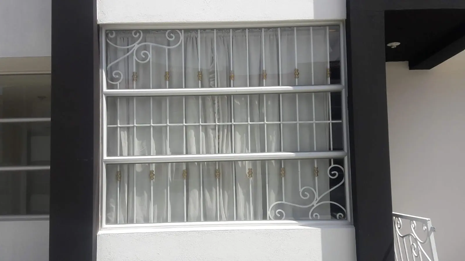 Cubre-ventana blanco de barrotes verticales con volutas