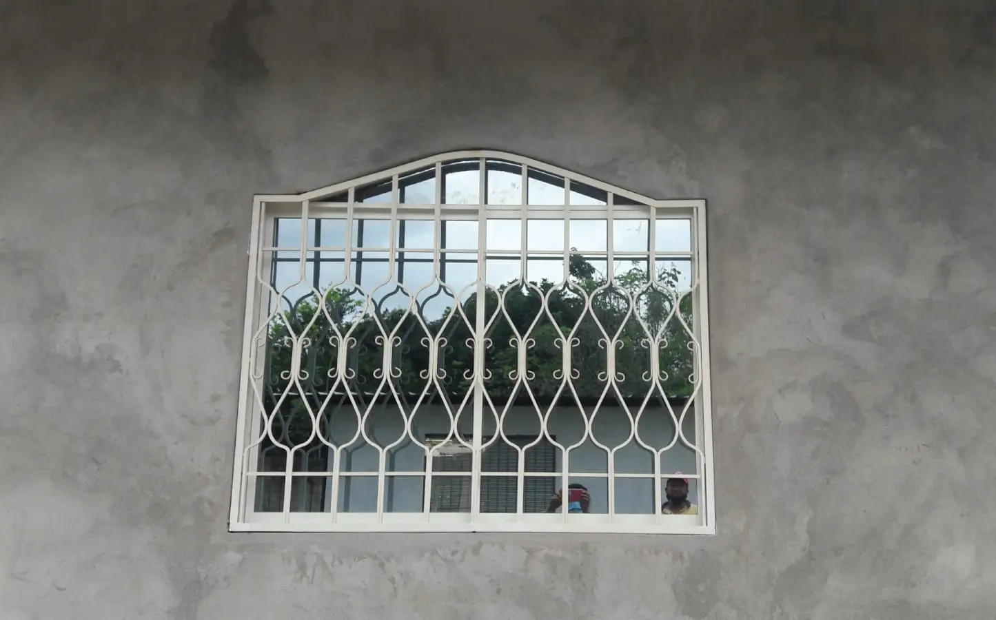 Cubre-ventana de hierro blanco con arco superior y volutas